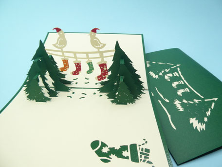 carte pop-up de noël chaussettes de noël étendues entre des sapins