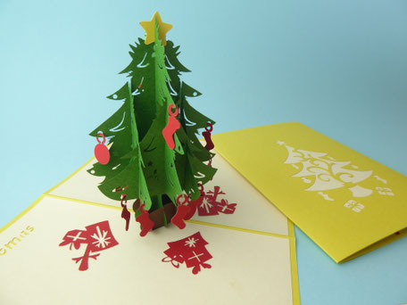 carte pop-up sapin de noël vert avec étoile jaune au sommet, suspensions de noël rouges et couverture dorée