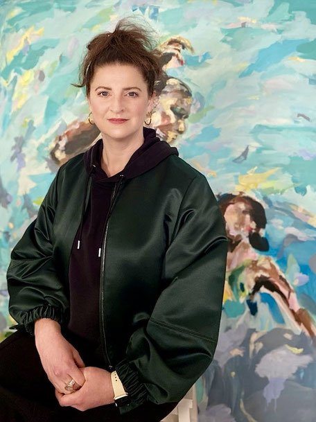 Künstlerin Zoë MacTaggart sitzt vor einem ihrer Gemälde