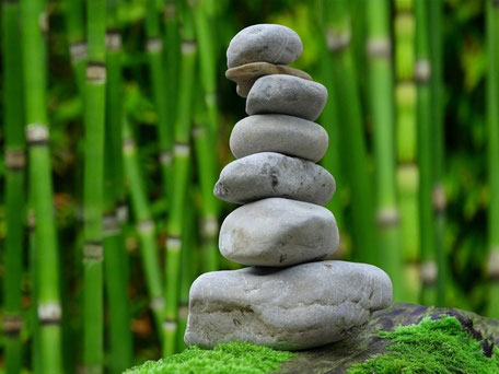 Steine aufgehäuft vor Bambus. Die Steine werden nach oben kleiner. Sie stehen als für die Wirbelsäule für den Workshop Wirbelsäulen-Qigong.