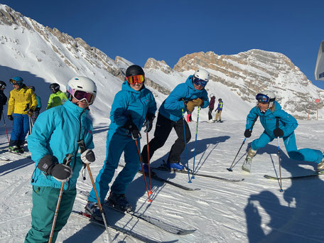 4 skilehrer stehen auf der piste auf die stoecke gelehnt, zugspitze
