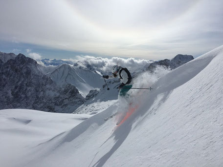 skifahrerin in steilem tiefschneehang vor bergpanorama