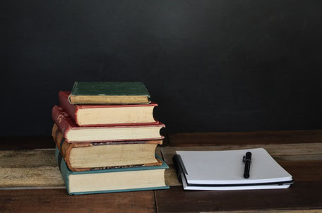 Des livres et un cahier avec un stylo sont sur une table.