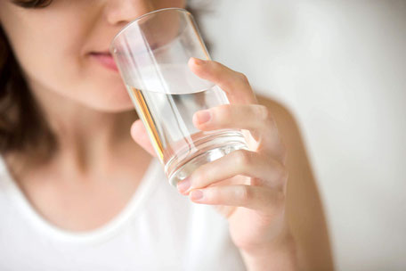 An asian lady drinking water from a glass