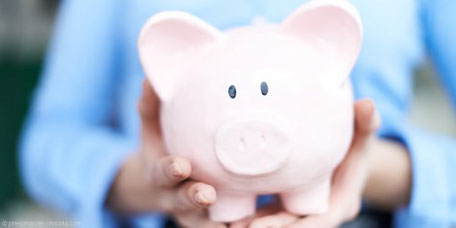 Sparschwein, das von zwei Händen gehalten wird.