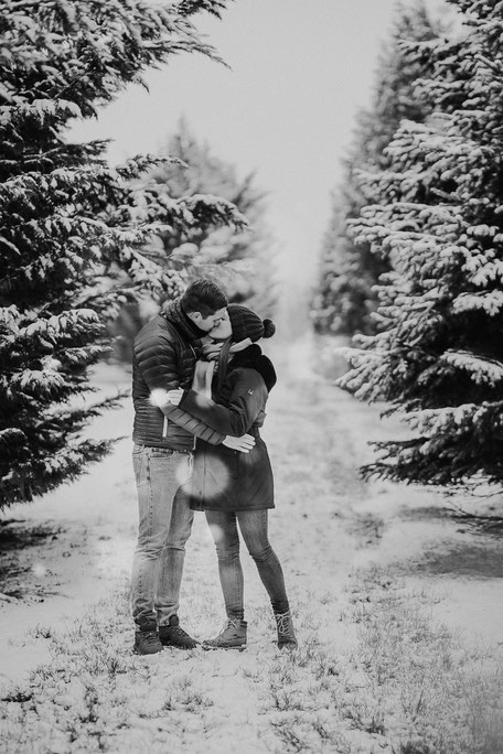 Schwarzweiss Bild eines sich im Schnee küssenden Paares