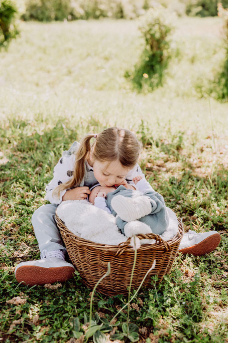 große Schwester küsst Baby auf die Wange bei Fotoshooting