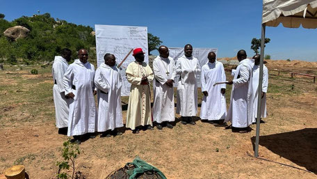 Eine Gruppe von Bischöfen in weißem Gewand vor der Baustelle eines Gymnasiums in Dodoma.