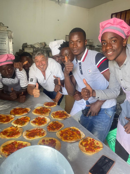 Bäckerei Lehrlinge die mit Daumen hoch in die Kamera lächeln und Pizzas gebacken haben