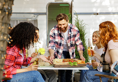 Freunde am Campingtisch vor Wohnmobil 2026