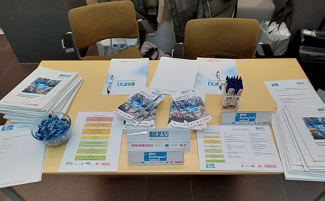Übersicht über den Info-Tisch mit Broschüren, Flyern, Kugelschreibern und Giveaways