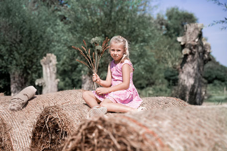 Natürliches Kindershooting mit Mädchen auf Heuballen – verspieltes Fotoshooting im ländlichen Stil