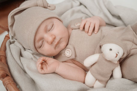 Ein neugeborenes Baby schläft friedlich in einem gemütlichen Körbchen, umhüllt von weichen Decken. Ein liebevoller Moment voller Geborgenheit in einer warmen Homestory-Atmosphäre.