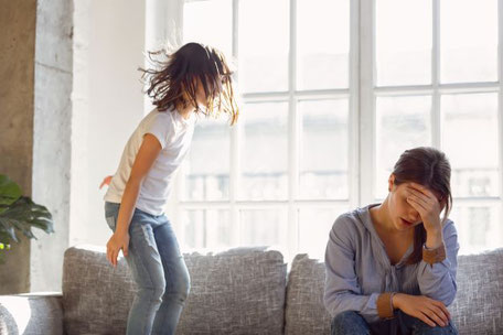 Ein Kind hüpft auf dem Sofa während die Mutter entnervt daneben sitzt als Motivbild für Vortragsreihe von Georgia Middel zum Psychologischen Basiswissen