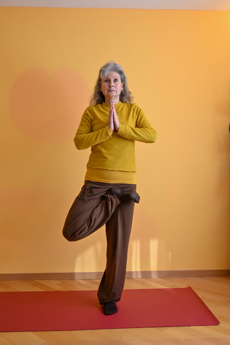 In tādāsana ist die Brustwirbelsäule sanft angehoben. Die Handhaltung vor dem Herzen drückt eine Zentrierung im Herzen aus. Der unsichere Stand auf einem Bein erfordert eine wache, bewusste Abstimmung mit dem äußeren Raum.