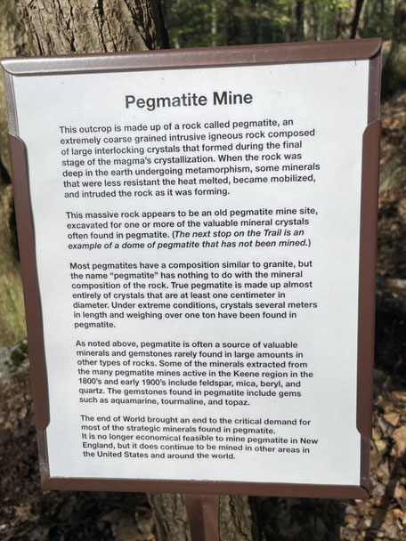 This is a small outcrop of pegmatite—a coarse, crystal-rich plutonic igneous rock—historically mined in this area for mineral and gem crystals such as feldspar, mica, quartz, tourmaline, and beryl.