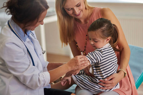 Kinderarzt Muenchen impft ein Kleinkind.