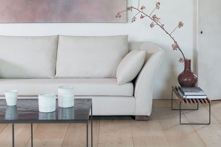 Weißes, gepolstertes Sofa mit Couchtisch und einer Vase