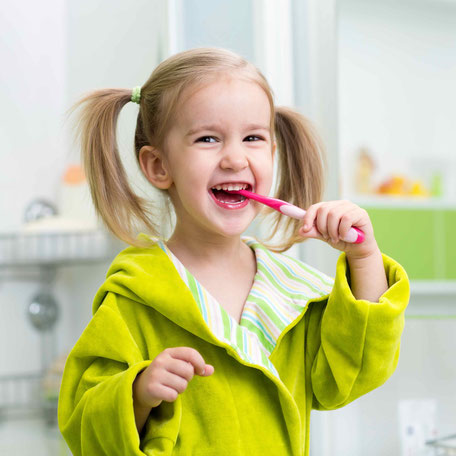 Ein lachendes Kind putzt sich die Zähne.