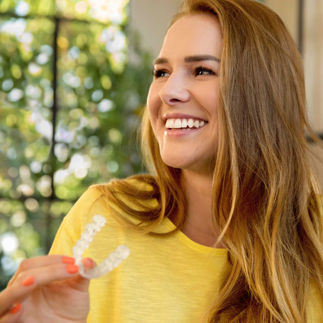 Lachende Erwachsene mit Transparenter Zahnschiene von Invisalign und Spark Aligner in der Praxis für Kieferorthopädie Schwabing-Freimann.
