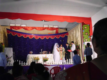 Christliche Hochzeit: das Paar gibt sich vor dem Prieser (mit goldenem Gewand) das Ja-Wort