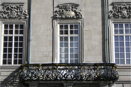 Baroque house facade with mullioned windows and richly decorated balcony 