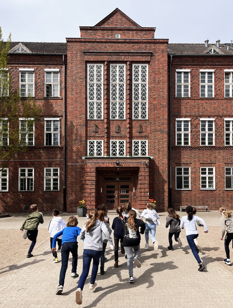 Kinder rennen auf die Schule zu.