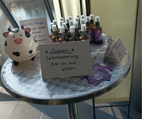 Ein Tisch mit energetisierten Essenzen und einer Kuh zum Geldeinwurf bei der Wohlfühlmesse