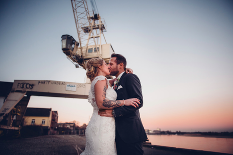 Ein Brautpaar küsst sich in einem Industriehafen.