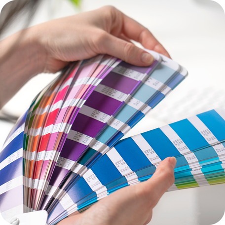 Hand hält einen Farbfächer zur Wahl der Sonderfarbe für den Druck