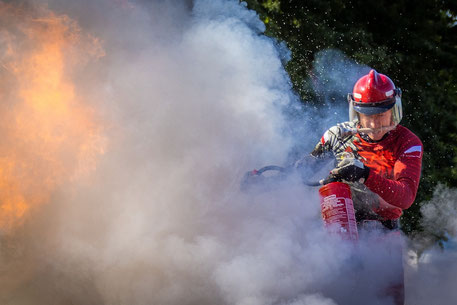 Feuerwehrmann in Schutzkleidung mit Feuerlöscher beim Löschen eines Brandes. REACH Anhang XVII (Beschränkungen) wurde um Eintrag 81, in dem es um PFAS in Feuerlöschschäumen geht, erweitert. PFAS sind Ewigkeitschemikalien, die nun REACH beschränkt werden..