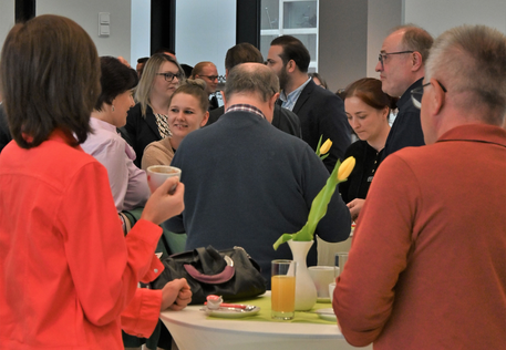 Teilnehmer:innen an Stehtischen im Foyer.