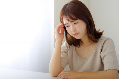 頭痛で頭に手をそえる女性