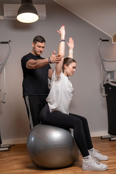 Physiotherapeut bei der Behandlung – Patientin trainiert mit Sitzball in der TrainierBar in Dinslaken