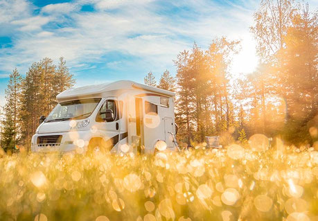 Wohnmobil auf Wiese bei Sonnenaufgang
