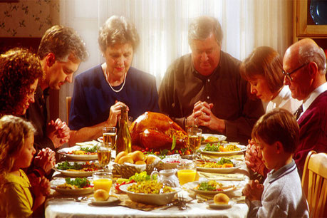 Family praying together over Thanksgiving dinner