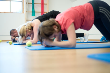 drei Personen auf einer Yogamatte bei einer Gruppe für Beckenbodentraining