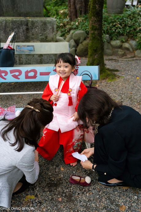 東京で七五三を迎えた赤い着物姿の女の子がベンチに座って微笑む姿
