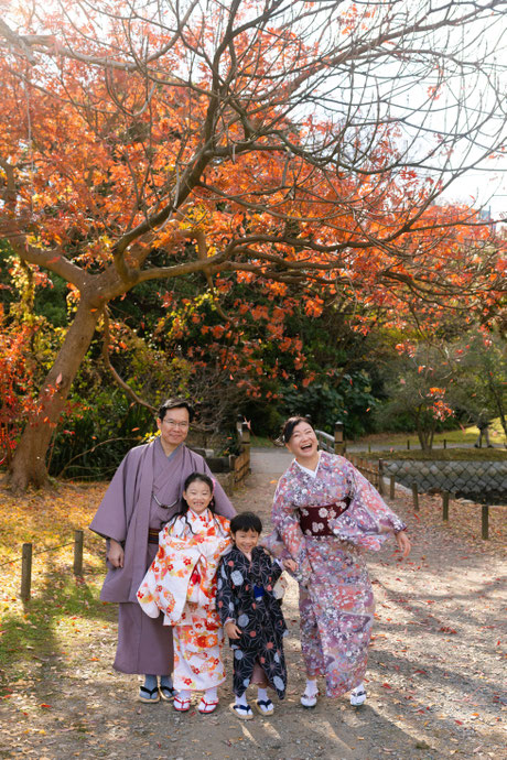 Family of four in kimono under autumn leaves in Tokyo — relaxed smiles, vibrant colors, and a picture-perfect moment