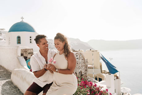 Glückliches Paar bei Verlobungsshooting vor malerischer Kulisse auf Santorini.