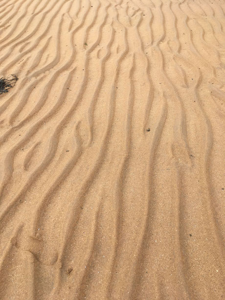 Das Meer malt schöne Wellenmuster in den Sand