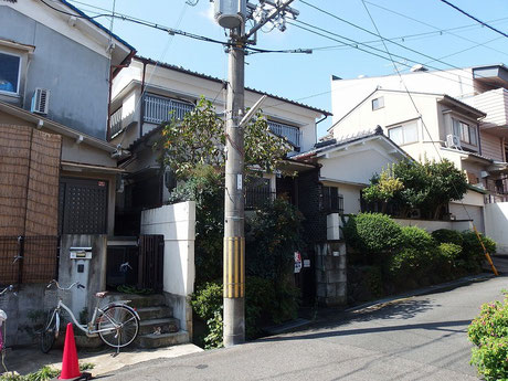 白い2階建てが建っている部分が敷地。道路面の舗装の切り替え部分が道路と専用通路の切り替わる部分と考えられます。切り替えより手前が建築基準法上の道路。本当にギリギリで接しています。2mあるかどうかというところ。