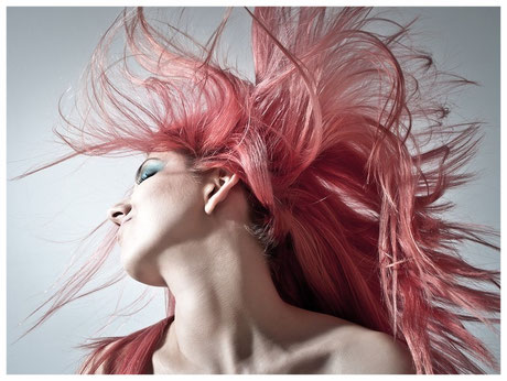 Eine junge Frau mit wilden pinken Haaren, die gerade ihren Kopf schüttelt.