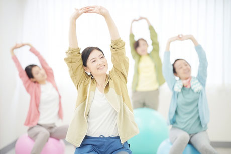 バランスボールに座ってストレッチをする女性