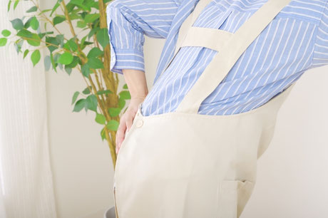 前かがみの姿勢で腰痛を感じている女性の画像