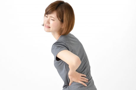 捻ると感じる腰の痛みに悩む女性の画像