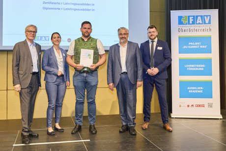 Foto mit Auszeichnung und Vertreter:innen des FAV OÖ