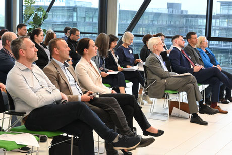 Publikum sitzt aufmerksam in einem lichtdurchfluteten Raum