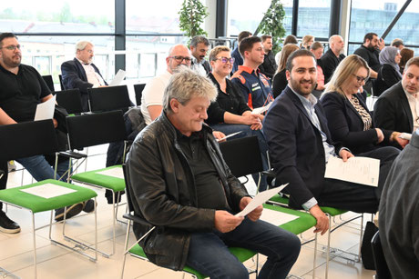 Männer und Frauen folgen interessiert einer Präsentation.