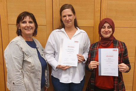 Sandra Kogler und Serbest Gül präsentieren ihre Zeugnisse, daneben ein Gratulantin